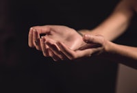 a woman's hands reaching out in front of a dark background